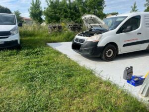 Entretien de véhicule utilitaire chez amlauto à Cadalen avec outils et palettes sur terrain extérieur,